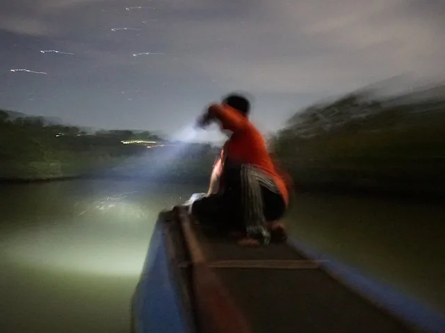 Personne sur un bateau éclairant avec une lampe torche sur la rivière Abatan la nuit