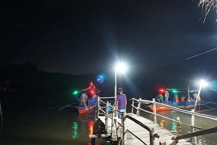 Boote legen nachts an einem beleuchteten Holzsteg am Abatan River an